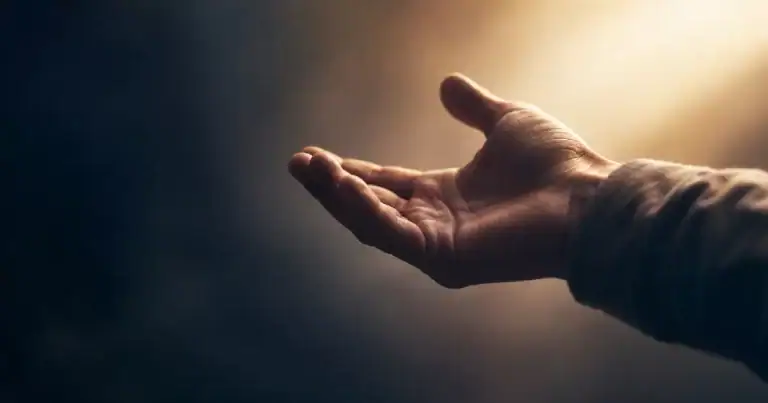A human hand extended palm up, reaching from soft darkness into warm light — representing an offer of connection.