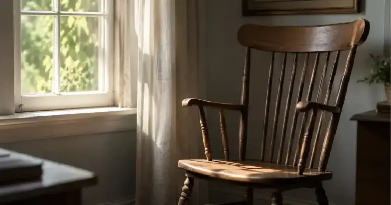 An empty wooden chair beside a window with soft morning light falling across the seat
